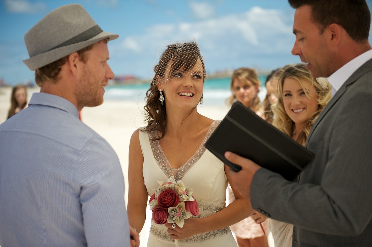 Beach wedding ceremony viewed from the side as the officiant reads the vows